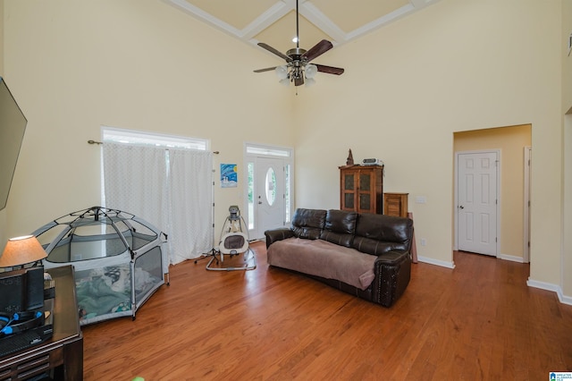living room featuring a high ceiling, coffered ceiling, and wood finished floors