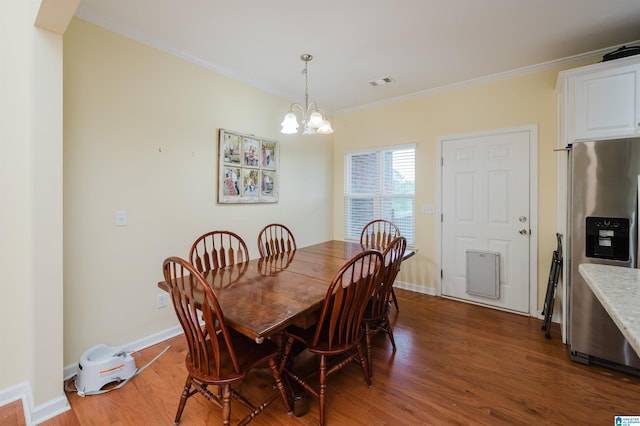 dining room featuring crown molding, a notable chandelier, baseboards, wood finished floors, and visible vents