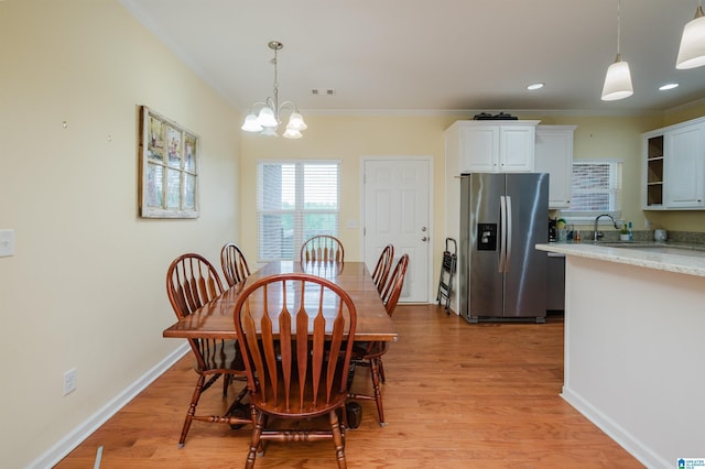 dining space featuring visible vents, light wood-style flooring, crown molding, and a chandelier