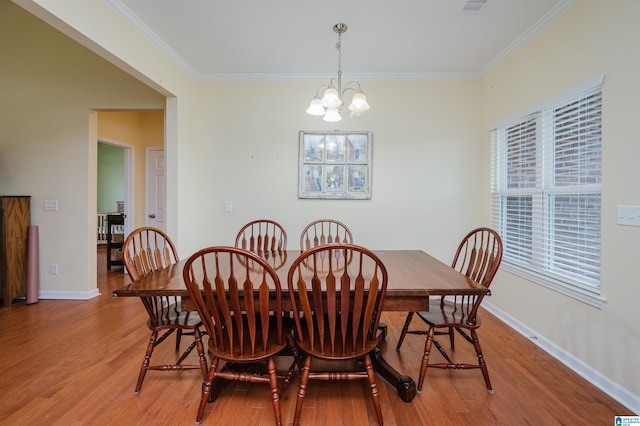 dining space with visible vents, baseboards, a chandelier, ornamental molding, and light wood-style flooring