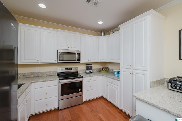 kitchen featuring visible vents, light wood finished floors, white cabinets, and stainless steel appliances