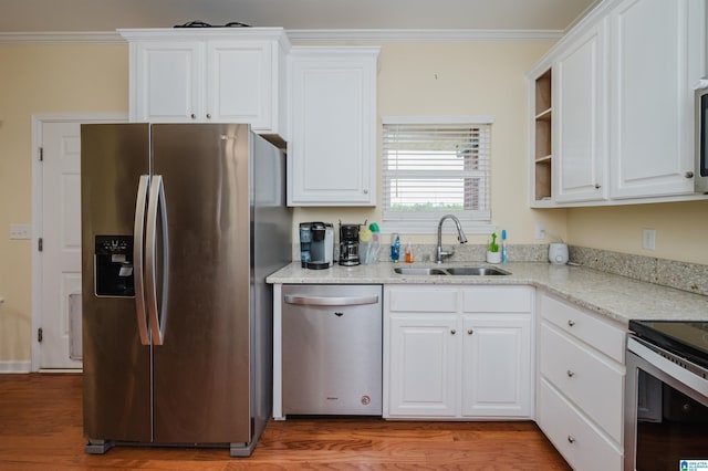 kitchen with crown molding, appliances with stainless steel finishes, a sink, and light wood-type flooring