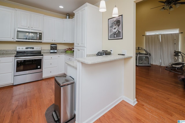 kitchen with appliances with stainless steel finishes, light stone counters, a peninsula, light wood finished floors, and white cabinetry