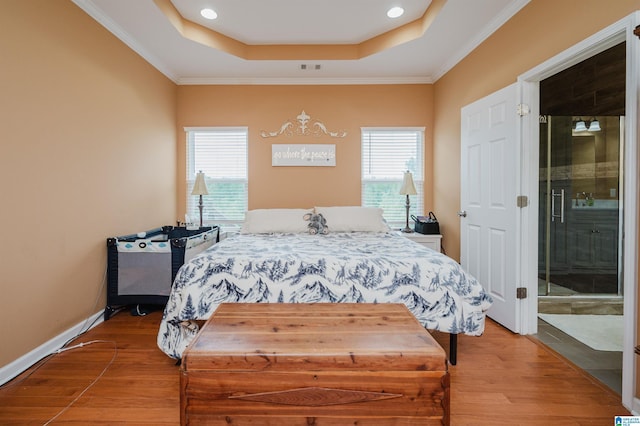 bedroom featuring light wood-style floors, a raised ceiling, and multiple windows