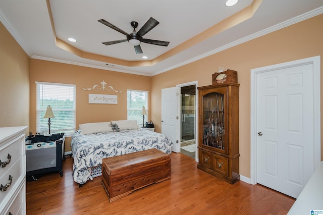 bedroom featuring ornamental molding, light wood-type flooring, recessed lighting, a tray ceiling, and a ceiling fan