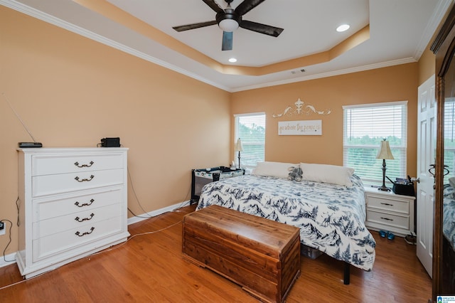 bedroom featuring light wood-style flooring, a raised ceiling, multiple windows, and ornamental molding