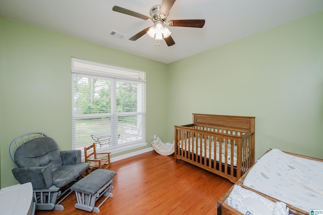 bedroom featuring visible vents, a ceiling fan, baseboards, and wood finished floors