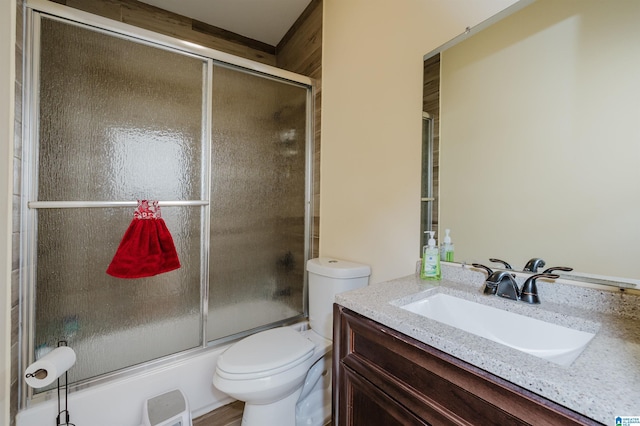 bathroom featuring toilet, enclosed tub / shower combo, and vanity
