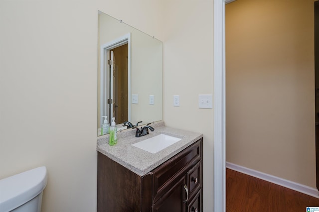 bathroom featuring vanity, baseboards, toilet, and wood finished floors