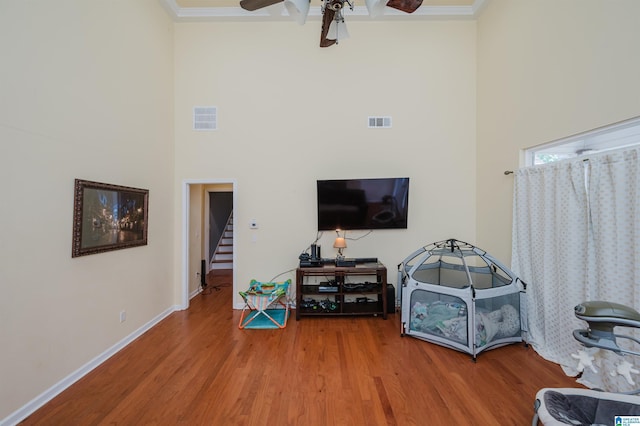living area with a ceiling fan, a high ceiling, and visible vents