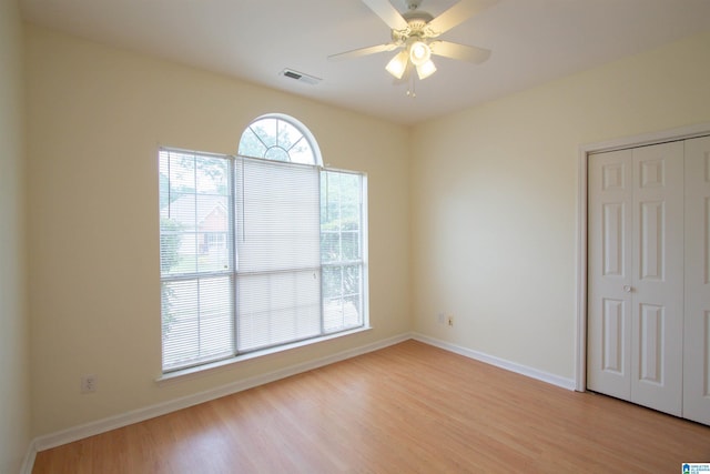 unfurnished room with baseboards, a ceiling fan, light wood finished floors, and visible vents