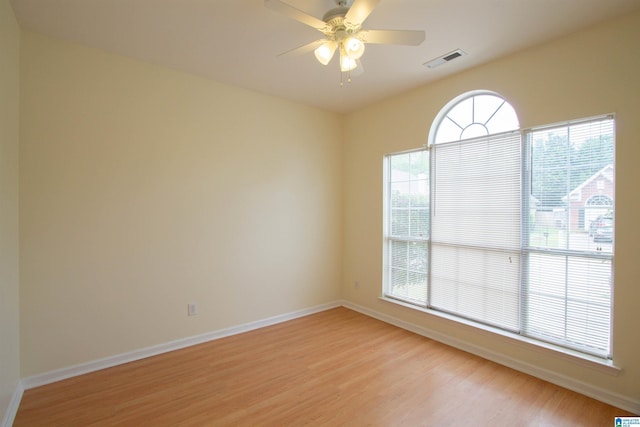 empty room featuring baseboards, a ceiling fan, light wood finished floors, and visible vents