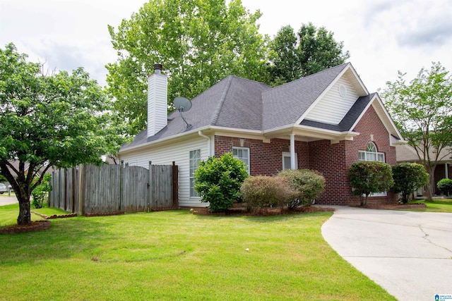view of front of property featuring roof with shingles, fence, a front lawn, and brick siding