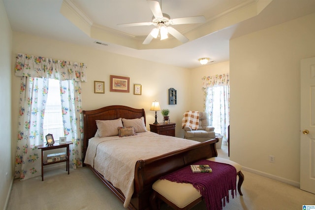 bedroom featuring light carpet, a ceiling fan, a tray ceiling, visible vents, and ornamental molding