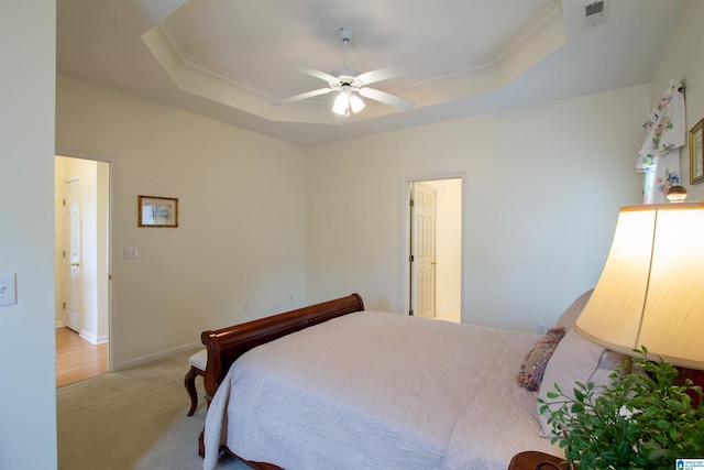 bedroom with light colored carpet, crown molding, and a tray ceiling