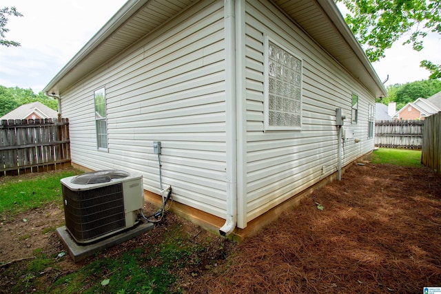 view of side of home with central air condition unit and fence private yard