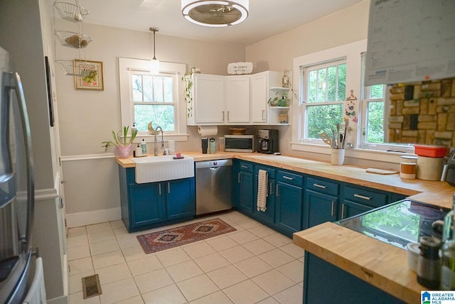 kitchen featuring a sink, appliances with stainless steel finishes, blue cabinets, and butcher block countertops