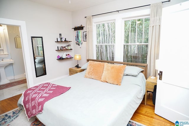 bedroom featuring baseboards, connected bathroom, and wood finished floors