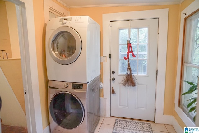 laundry room featuring light tile patterned floors, baseboards, ornamental molding, and stacked washer / dryer