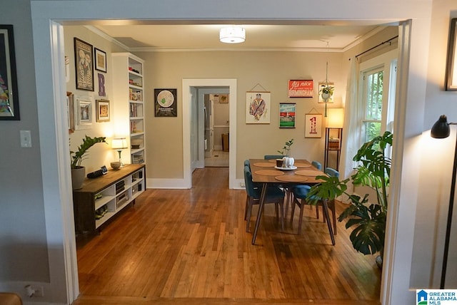 dining area with crown molding, baseboards, and hardwood / wood-style flooring