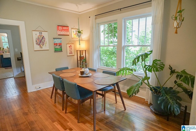 dining space with crown molding, baseboards, and light wood finished floors