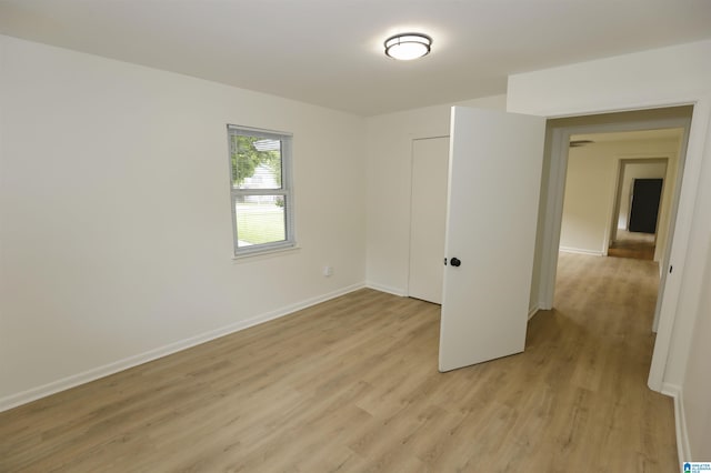 spare room with baseboards and light wood-style floors