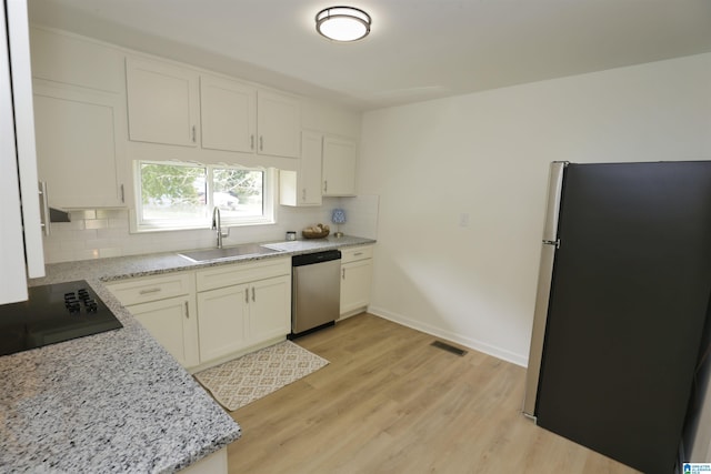 kitchen featuring appliances with stainless steel finishes, tasteful backsplash, light wood-type flooring, a sink, and baseboards