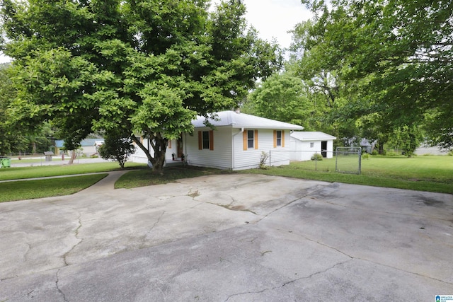 view of front of home featuring fence, a chimney, concrete driveway, and a front lawn
