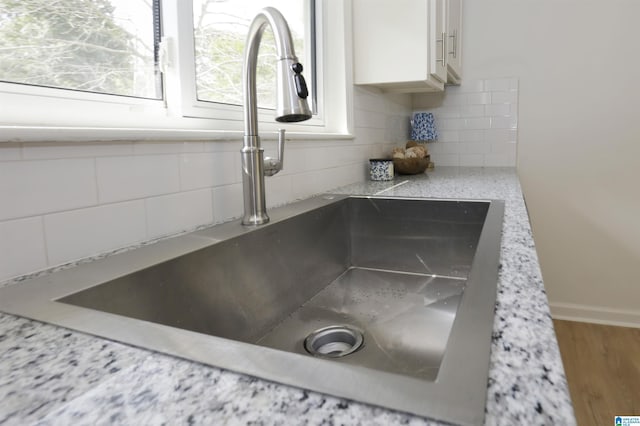 details with baseboards, a sink, backsplash, and white cabinets