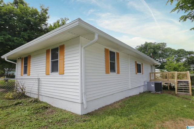 view of side of property with fence, a yard, a deck, and cooling unit