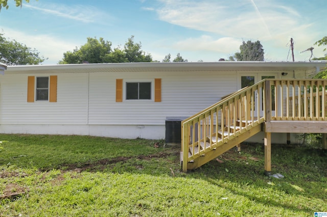 back of property with central AC, a yard, and a wooden deck