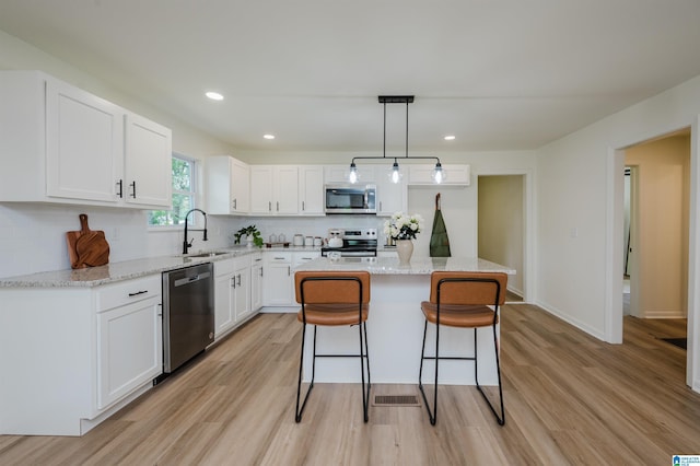 209 Nabors Ave, Hueytown, AL 35023 - kitchen with a breakfast bar area, a sink, light wood finished floors, appliances with stainless steel finishes, and backsplash