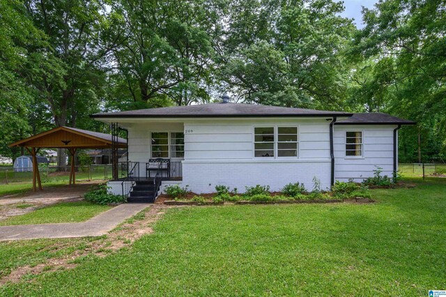209 Nabors Ave, Hueytown, AL 35023 - view of front of house featuring fence, a front yard, brick siding, a porch, and a carport