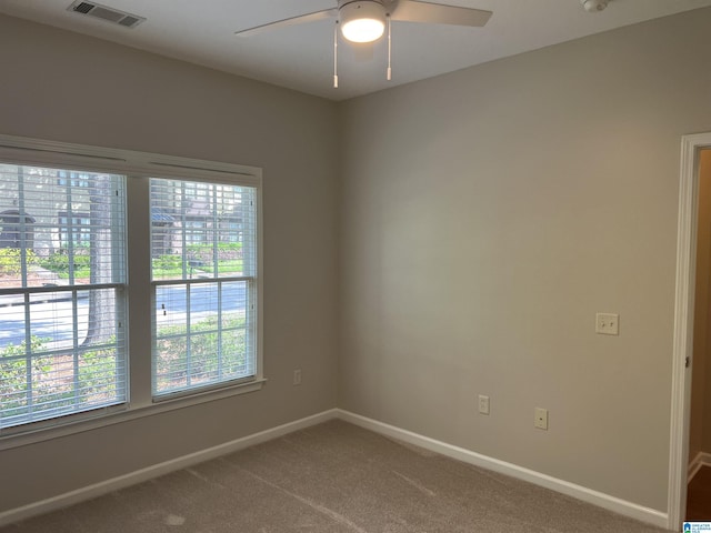 carpeted spare room featuring baseboards, a wealth of natural light, ceiling fan, and visible vents
