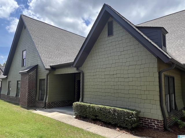 view of side of home featuring roof with shingles and a yard