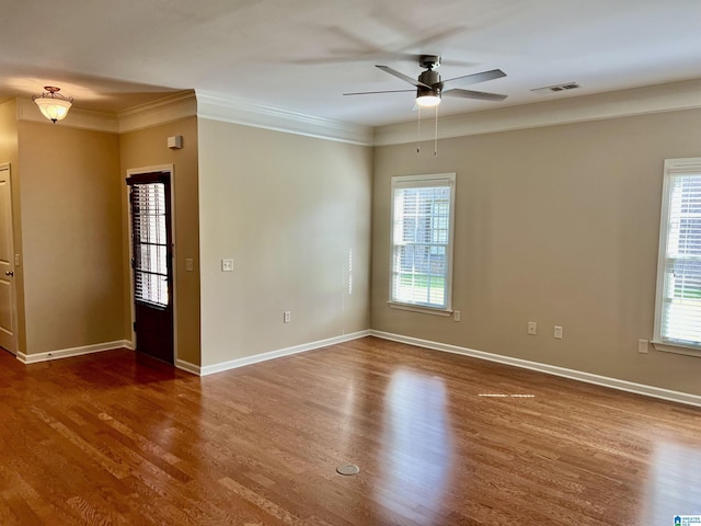 unfurnished room featuring visible vents, a ceiling fan, wood finished floors, and a wealth of natural light