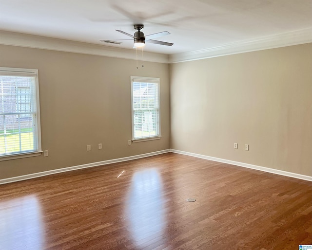unfurnished room with plenty of natural light, a ceiling fan, dark wood-style floors, and visible vents