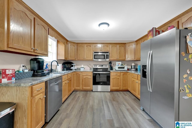 kitchen featuring a sink, appliances with stainless steel finishes, light wood finished floors, and light countertops