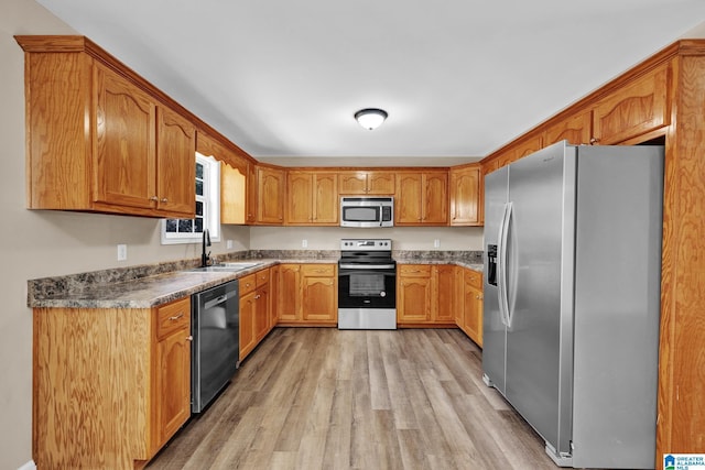 kitchen featuring light wood-style floors, stainless steel appliances, brown cabinets, and a sink