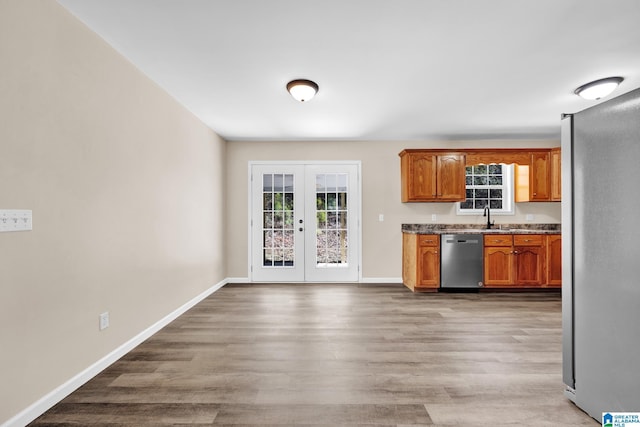 kitchen featuring baseboards, light wood finished floors, appliances with stainless steel finishes, and french doors