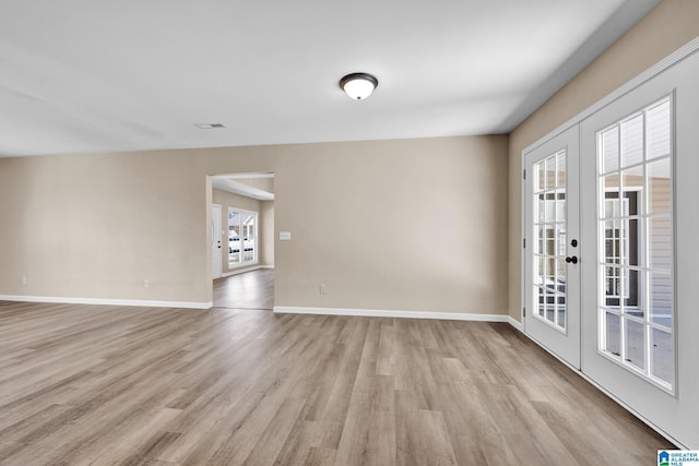 unfurnished room with french doors, baseboards, and light wood-type flooring