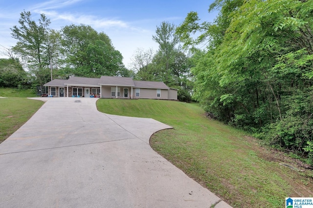 ranch-style home featuring concrete driveway and a front yard