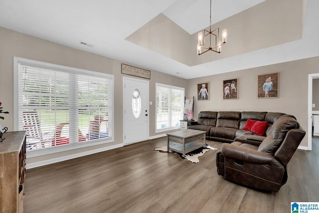 living area with baseboards, visible vents, wood finished floors, and a chandelier
