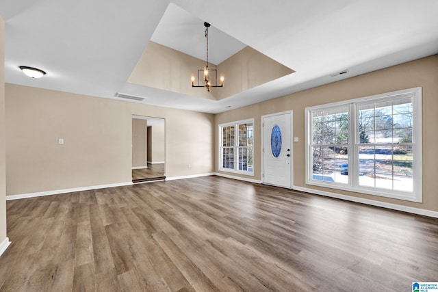 unfurnished living room with wood finished floors, a chandelier, and visible vents
