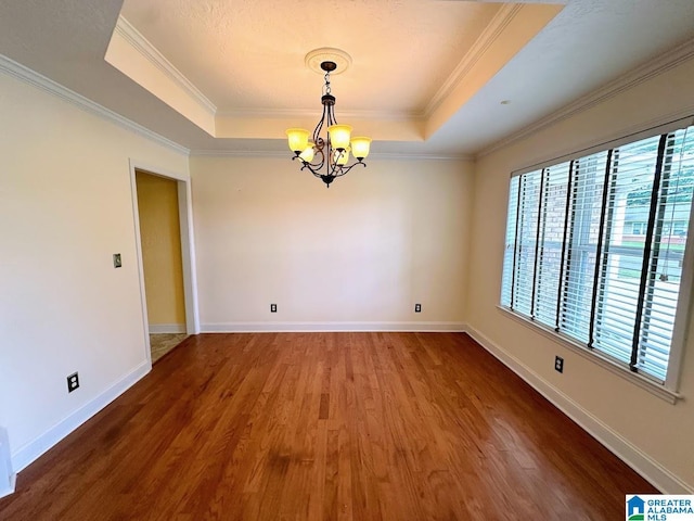 unfurnished room featuring a healthy amount of sunlight, a tray ceiling, and wood finished floors