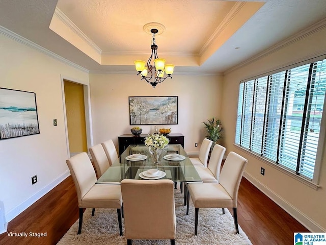 dining space with a raised ceiling, plenty of natural light, and wood finished floors