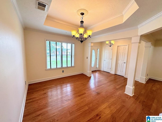 interior space with visible vents, crown molding, wood finished floors, a tray ceiling, and a notable chandelier