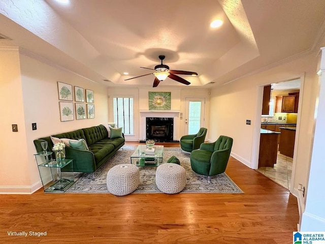living area featuring wood finished floors, baseboards, recessed lighting, a raised ceiling, and a ceiling fan