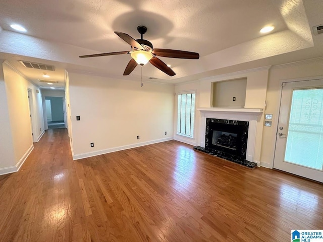 unfurnished living room with a fireplace, a ceiling fan, wood finished floors, and visible vents