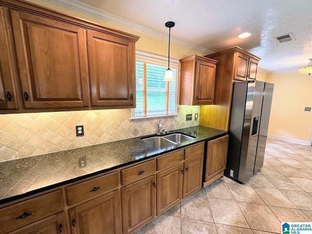 kitchen featuring visible vents, dark countertops, stainless steel refrigerator with ice dispenser, a sink, and backsplash